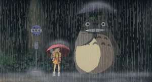 Escena de Mi vecino Totoro en la que aparecen una de las niñas protagonistas y Totoro. Están esperando en una estación de autobús bajo la lluvia. Ambos agarran sendos paraguas. 